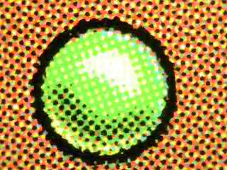 A green symbol under macro magnification, showing color layering and dot registration