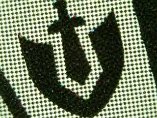 Lorcana ink symbol under macro magnification, showing the halftone dot printing pattern